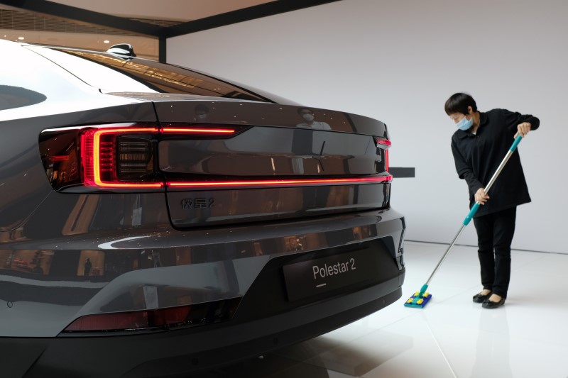 © Reuters. Worker cleans the floor near a Polestar 2 electric sedan at a shopping mall in Shanghai