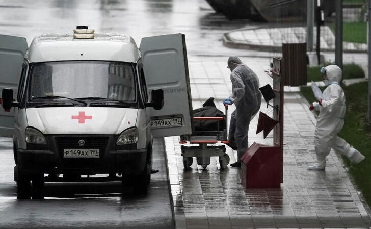 &copy; Reuters. Медики в защитных костюмах везут каталку к машине скорой помощи возле подмосковной больницы