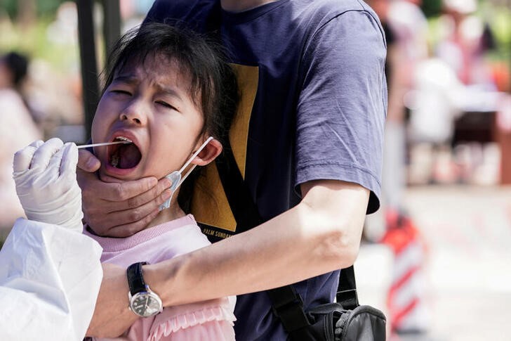 &copy; Reuters. Una niña reacciona mientras se somete a un test de ácido nucleico en Wuhan, China.