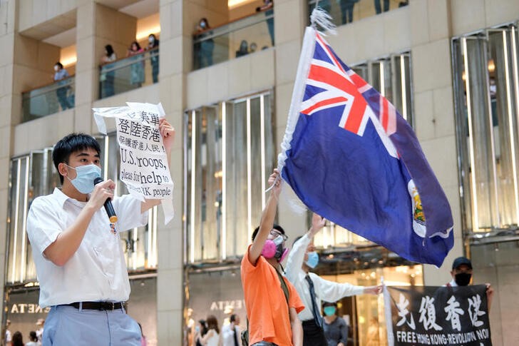 &copy; Reuters. Manifestantes pró-democracia com máscaras de proteção empunham bandeira colonial britânica de Hong Kong