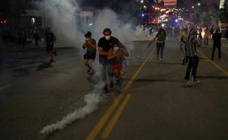 © Reuters. Un hombre ayuda a una mujer después de recibir gas lacrimógeno durante una protesta en St Louis, Missouri, EEUU