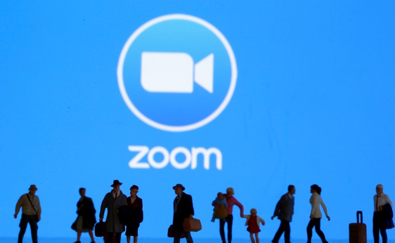 &copy; Reuters. Small toy figures are seen in front of diplayed Zoom logo