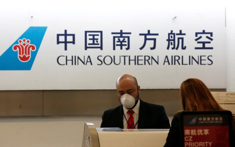 &copy; Reuters. FILE PHOTO: A China Southern Airlines employee wears a surgical mask as a preventive measure in light of the coronavirus outbreak in China, while he attends a customer behind the counter at Benito Juarez international airport in Mexico City