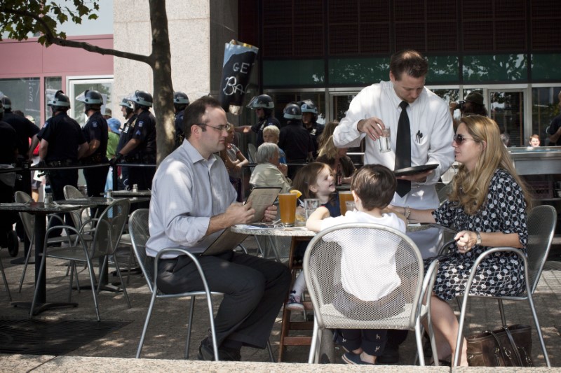 &copy; Reuters. A family is served drinks at a restaurant while Occupy Wall Street activists protest through the streets of New York&apos;s Financial District on the one-year anniversary of the movement, in New York