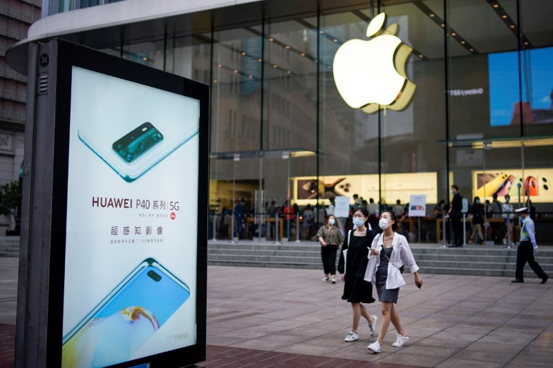 &copy; Reuters. People wearing protective face masks walk next to a Huawei advertisement and an Apple store in Shanghai following an outbreak of the novel coronavirus disease (COVID-19), in Shanghai