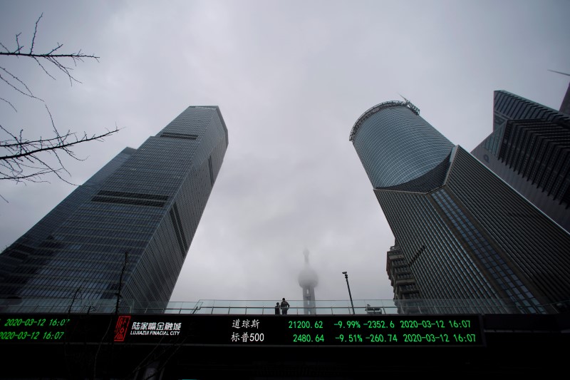 &copy; Reuters. People are seen on a pedestrian overpass with an electronic board showing the Dow Jones and S&amp;P 500 indexes, following an outbreak of the novel coronavirus in the country, at Lujiazui financial district in Shanghai