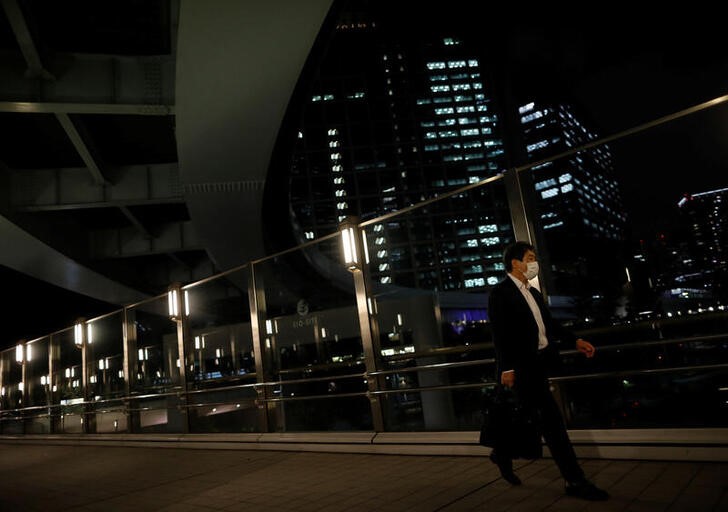 &copy; Reuters. Un uomo con una maschera protettiva cammina per le strade di Tokyo