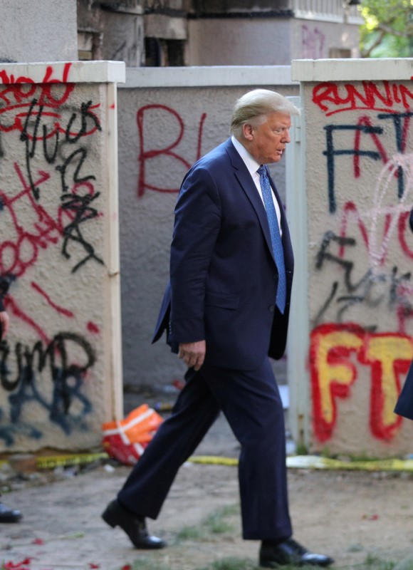 © Reuters. FILE PHOTO: U.S. President Trump walks past a building defaced with graffiti by protestors in Washington