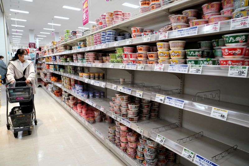 © Reuters. FILE PHOTO: A shopper wearing a protective mask looks at shelves at a supermarket in Tokyo