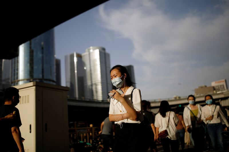 &copy; Reuters. People wearing face masks following the coronavirus disease (COVID-19) outbreak walk by a major thoroughfare in Beijing