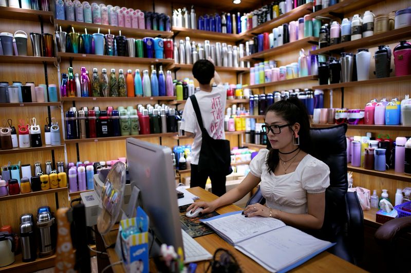 © Reuters. Deng Jinling, manager of Lucky Bird Trade Co. checks her online store on a company at a cup products shop at the Yiwu Wholesale Market following an outbreak of the novel coronavirus disease (COVID-19), in Yiwu