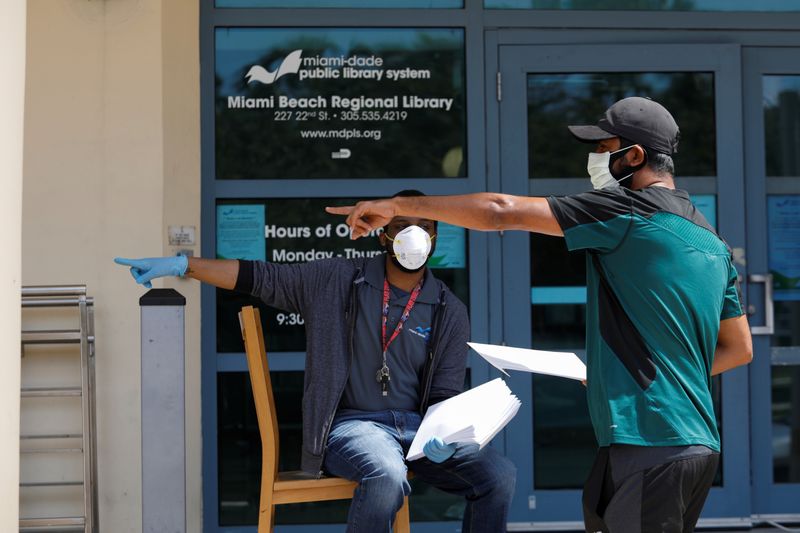 &copy; Reuters. A man speaks with a library worker after receiving an unemployment form, as the outbreak of coronavirus disease (COVID-19) continues, in Miami Beach