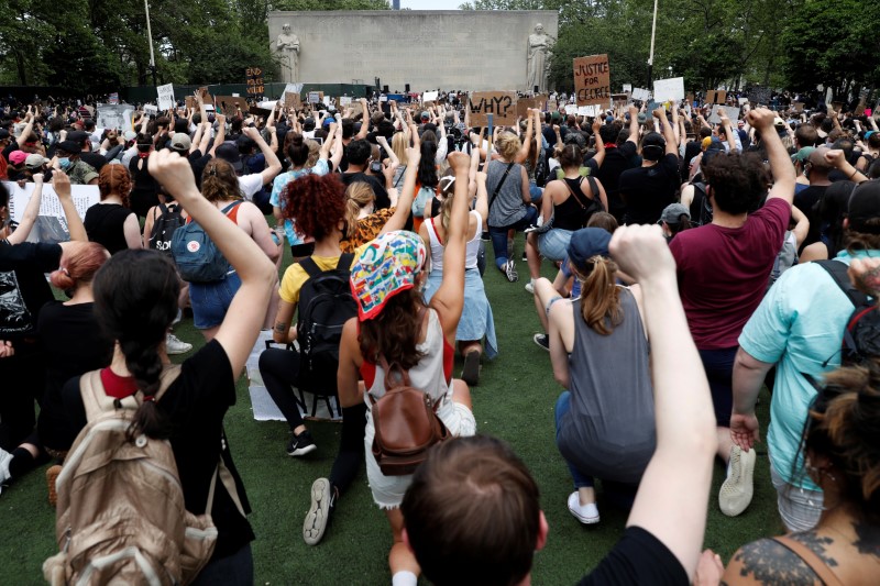 &copy; Reuters. Personas se arrodillan y levantan los puños mientras asisten a un servicio conmemorativo público después de la muerte en custodia policial de George Floyd en Mineápolis, EEUU