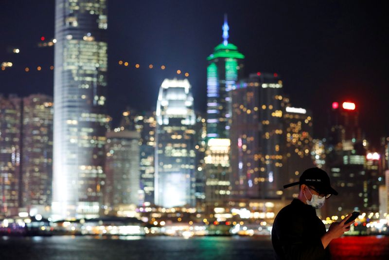 &copy; Reuters. FILE PHOTO: A man wears mask to prevent a new coronavirus outbreak as he uses his mobile, with skyline in the background of Hong Kong