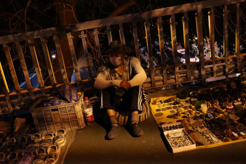 &copy; Reuters. Street vendor waits for customers at his stall on a footbridge in Beijing