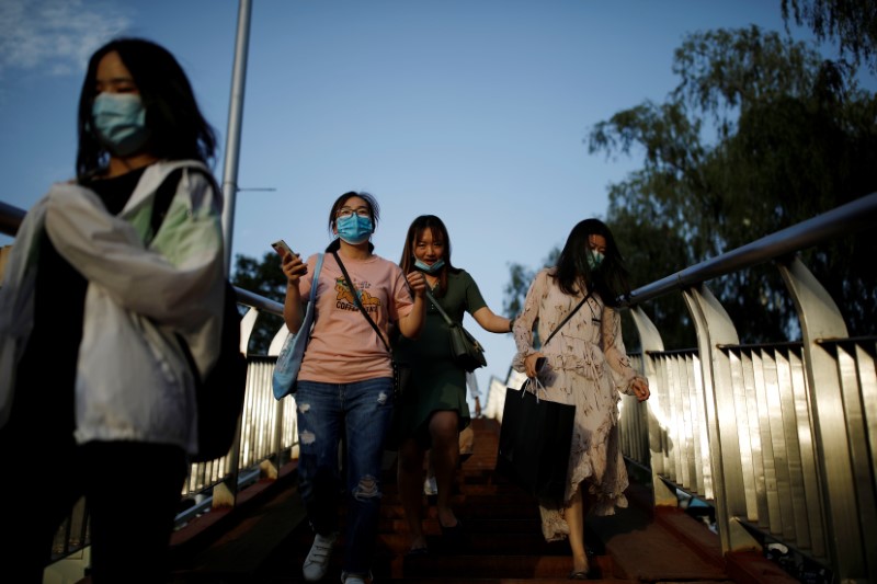 &copy; Reuters. People wearing face masks walk on a footbridge in Beijing