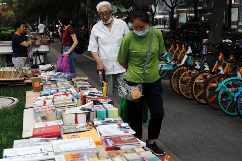 © Reuters. People look at books displayed at a street stall at the Sanlitun shopping area in Beijing