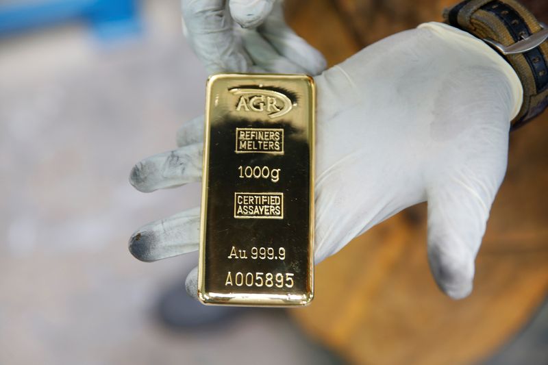 &copy; Reuters. Сотрудник со слитком золота весом 1 кг в компании African Gold Refinery в Уганде