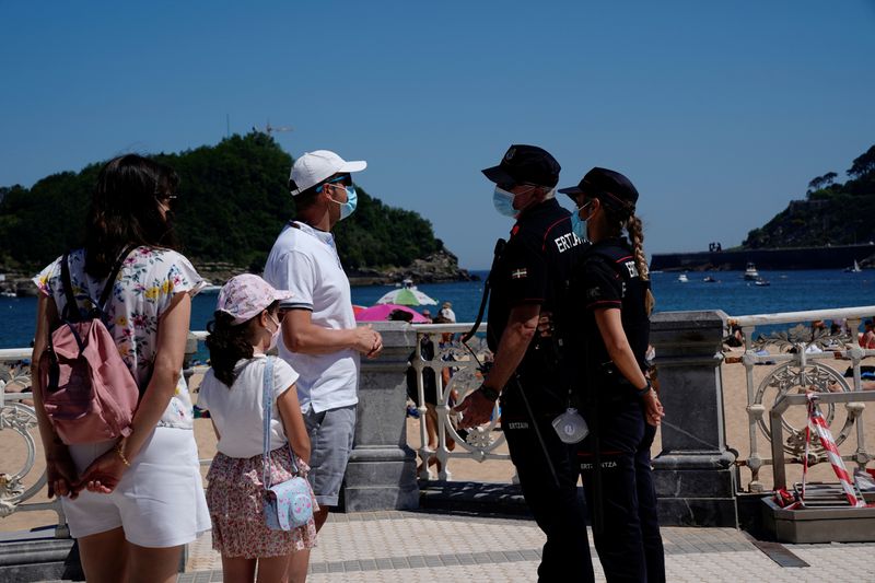&copy; Reuters. Una familia con mascarillas habla con la policía en la playa de Ondarreta en San Sebastián