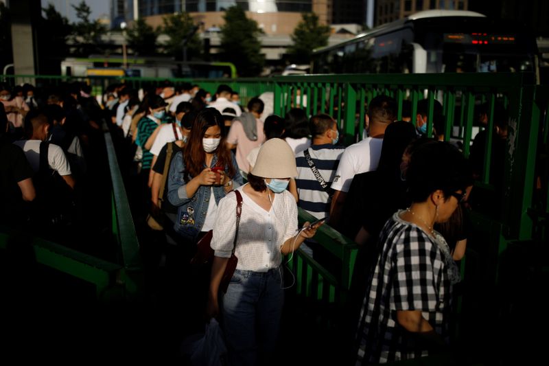 &copy; Reuters. FILE PHOTO: People wearing face masks following the coronavirus disease (COVID-19) outbreak line up at a bus station in Beijing