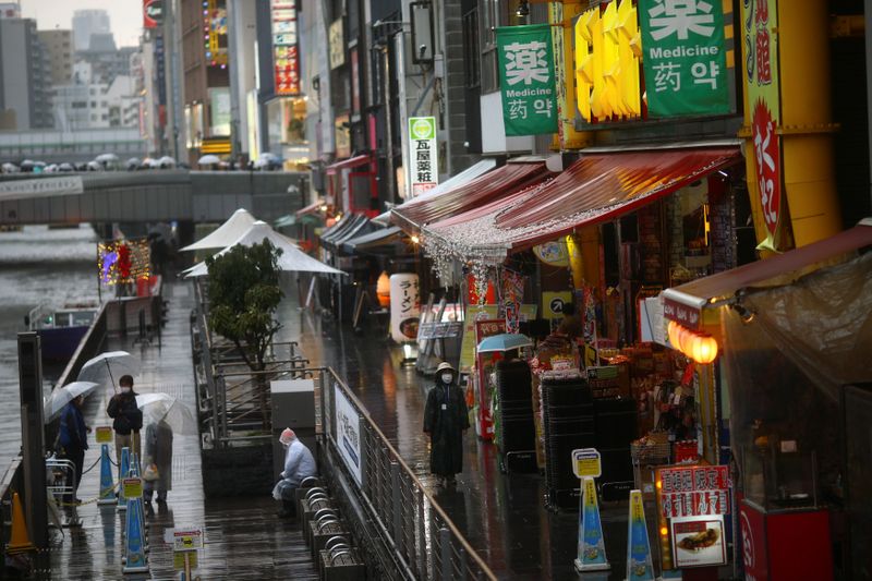 © Reuters. A woman, wearing protective mask following an outbreak of the coronavirus disease (COVID-19), walks on an almost empty street in the Dotonbori entertainment district of Osaka