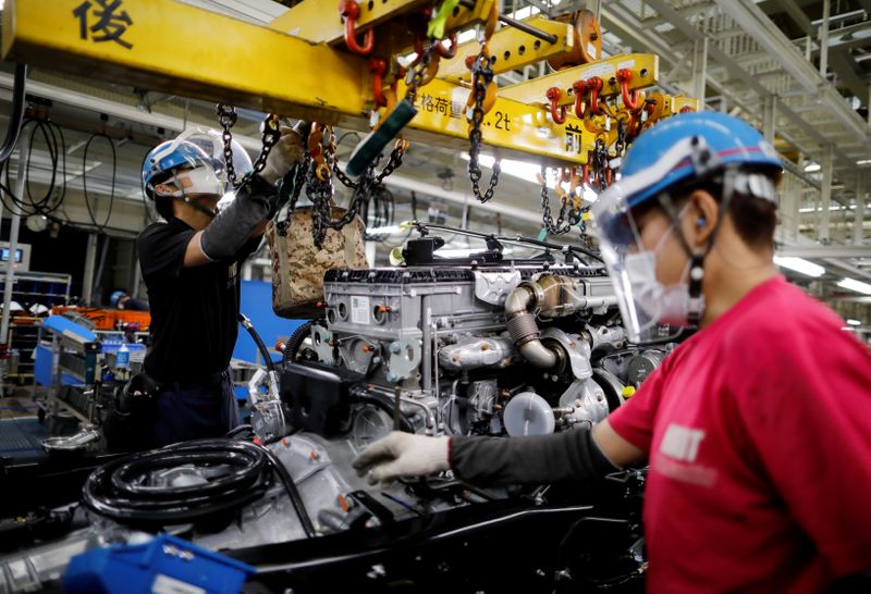 &copy; Reuters. FOTO DE ARCHIVO: Trabajadores con mascarilla trabajan en la línea de ensamblaje de automóviles en la fábrica de Kawasaki de Mitsubishi Fuso Truck and Bus Corp., propiedad de la empresa alemana Daimler AG, en Kawasaki, al sur de Tokio, Japón