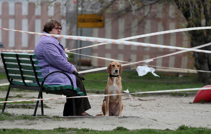 &copy; Reuters. FILE PHOTO: A woman sits with her dog in a taped-off playground amid the coronavirus outbreak in Moscow, Russia