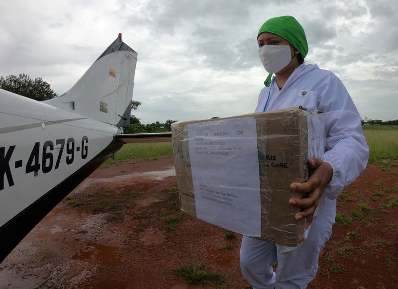 &copy; Reuters. Bacteriologist Diana Carolina Galvan from the Hospital de La Primavera using protection elements carries a box with samples of the coronavirus disease (COVID-19) that will be processed in Bogota, in La Primavera