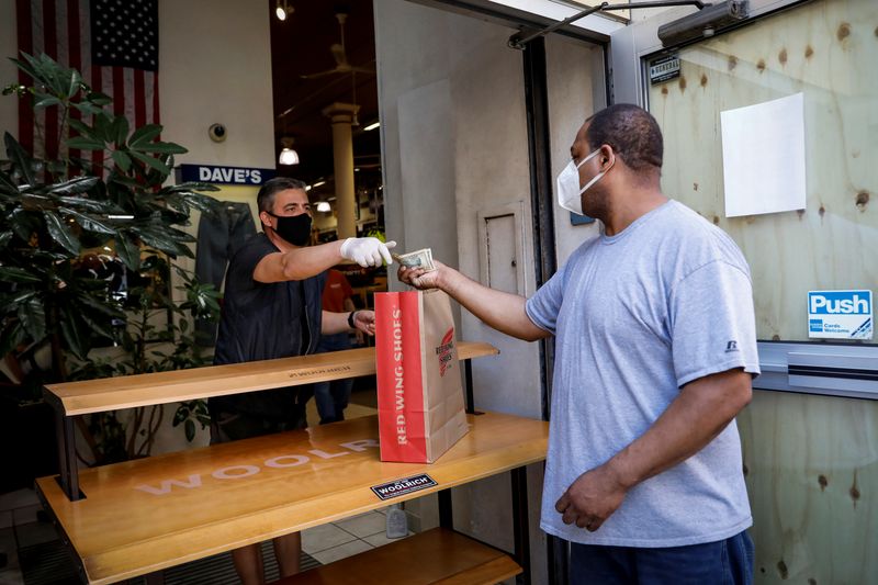 &copy; Reuters. A customer pays for his purchase in the doorway of Dave&apos;s New York, a retail store, as phase one of reopening after lockdown begins, during the outbreak of the coronavirus disease (COVID-19) in New York