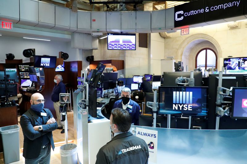 &copy; Reuters. Traders wearing masks work, on the first day of in person trading since the closure during the outbreak of the coronavirus disease (COVID-19) on the floor at the NYSE in New York