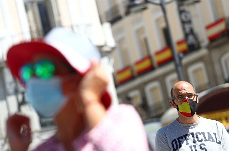 © Reuters. Foto del viernes de un hombre con máscara en la Puerta del Sol, en Madrid, mientras se realiza un minuto de silencio por los muertos por la pandemia de coronavirus