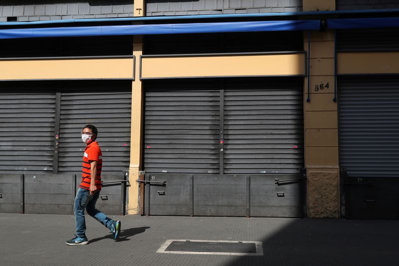 &copy; Reuters. Homem passa por comércio fechado no centro de São Paulo (SP) em meio à pandemia de coronavírus