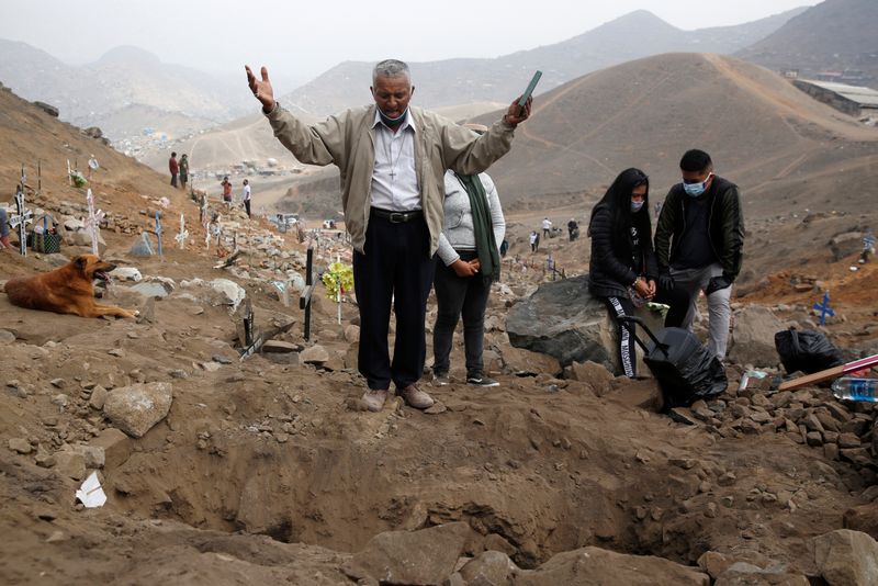 &copy; Reuters. Imagen de archivo de un hombre rezando cerca de familiares en el funeral de un ser querido que murió por COVID-19, en el Cementerio Nueva Esperanza, en Lima, Perú