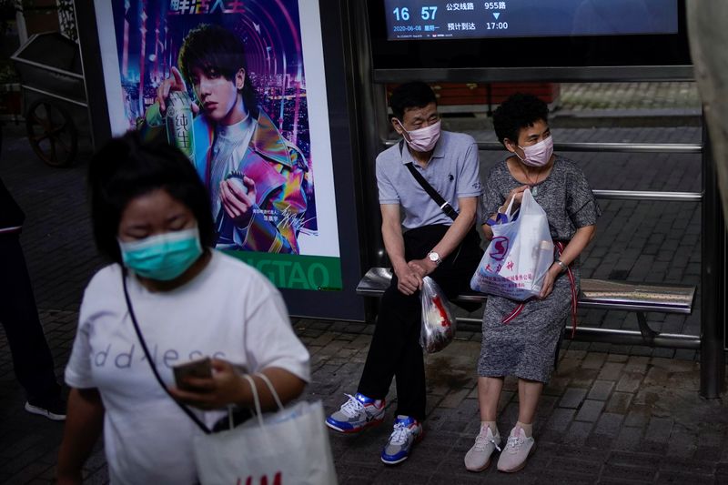 &copy; Reuters. FILE PHOTO: People wearing face masks wait for a bus on a street in Shanghai