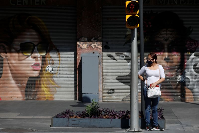 © Reuters. FILE PHOTO:  A woman stands by a pedestrian crossing light on the street as the outbreak of the coronavirus disease (COVID-19) continues in Mexico City