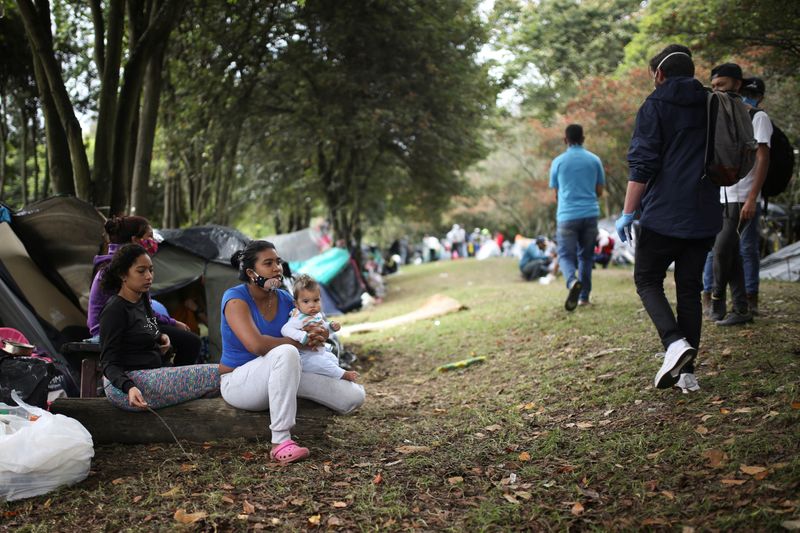 &copy; Reuters. Una mujer inmigrante venezolana alza su bebé fuera de una tienda de campaña en un campamento improvisado durante la pandemia de coronavirus en las afueras de Bogotá