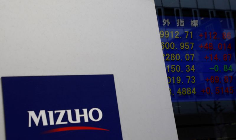 &copy; Reuters. Mizuho Financial Group&apos;s logo is seen next to an electronic board showing stock prices indexes at a branch of Mizuho Securities in Tokyo