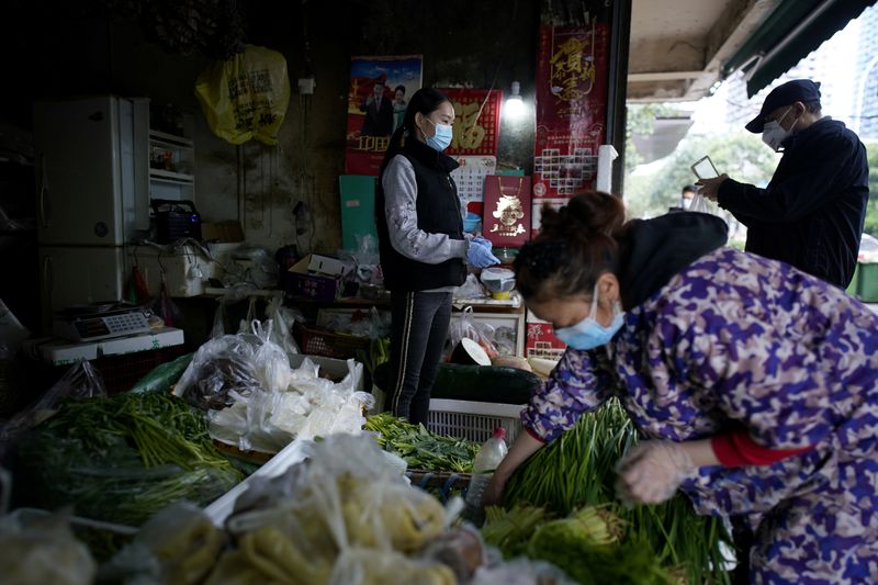 © Reuters. FILE PHOTO: People wearing face masks buy vegetables at a street market in Wuhan