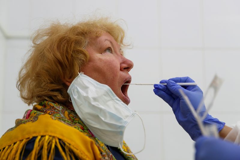 &copy; Reuters. A healthcare worker takes a swab from a woman during testing for the coronavirus disease (COVID-19) and antibodies at a clinic in Moscow