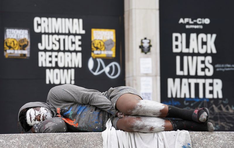 &copy; Reuters. Un hombre duerme en un banco frente a carteles de protesta de Black Lives Matter cerca de la Casa Blanca en Washington, Estados Unidos.