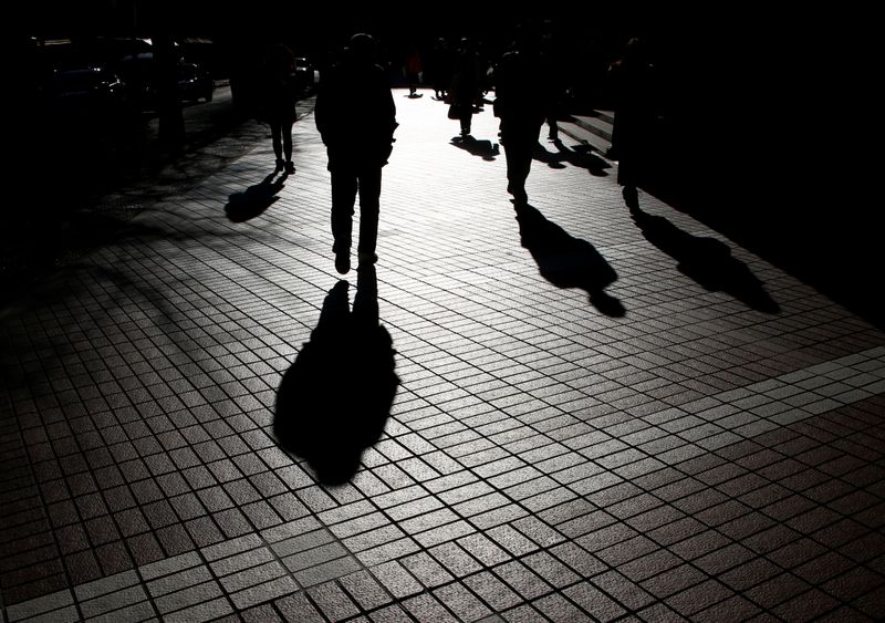 &copy; Reuters. Pedestrians cast shadows as they make their way at a financial district in Tokyo