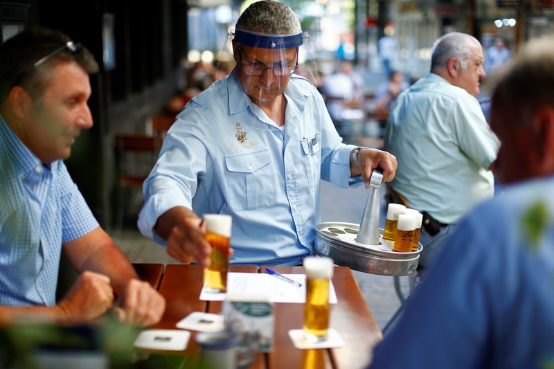 &copy; Reuters. Imagen de archivo de un camarero con un escudo facial sirviendo cervezas a unos clientes en la terraza de un bar en Colonia, Alemania.