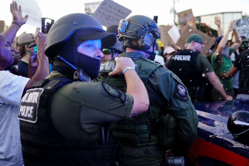 © Reuters. Police officers escort a police SUV from a crowd of protesters while bottles of water are thrown at them during a rally against racial inequality and the police shooting death of Rayshard Brooks, in Atlanta