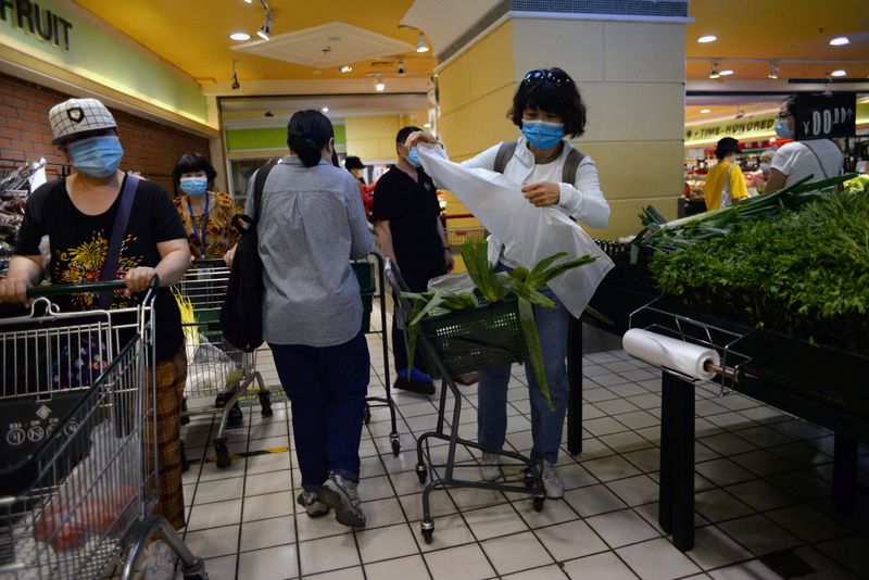 © Reuters. People wearing face masks shop for vegetables at a supermarket, following new cases of coronavirus disease (COVID-19) infections in Beijing