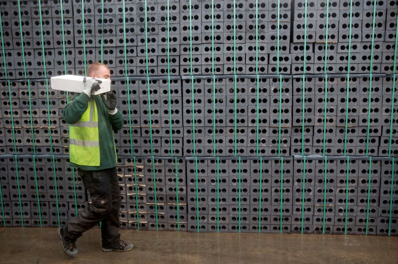 © Reuters. A worker walks past bricks at the Vauxhall depot of building material supplier Travis Perkins in London