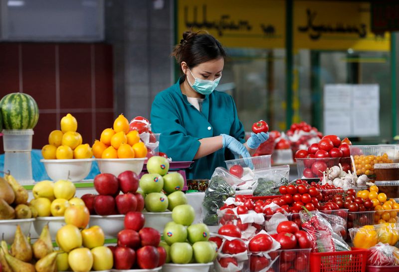 © Reuters. Продавец в защитной маске на рынке в Алма-Ате