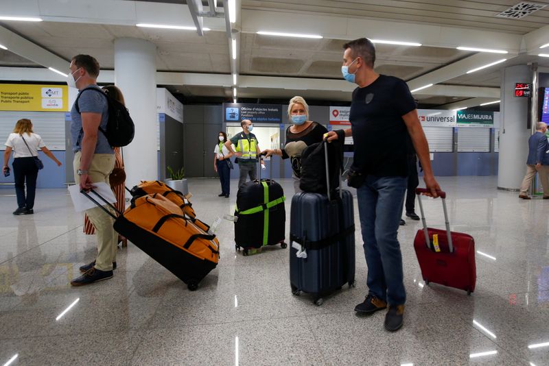 © Reuters. Turistas alemanes portando mascarillas llegan al aeropuerto de Palma de Mallorca, en Palma de Mallorca, España