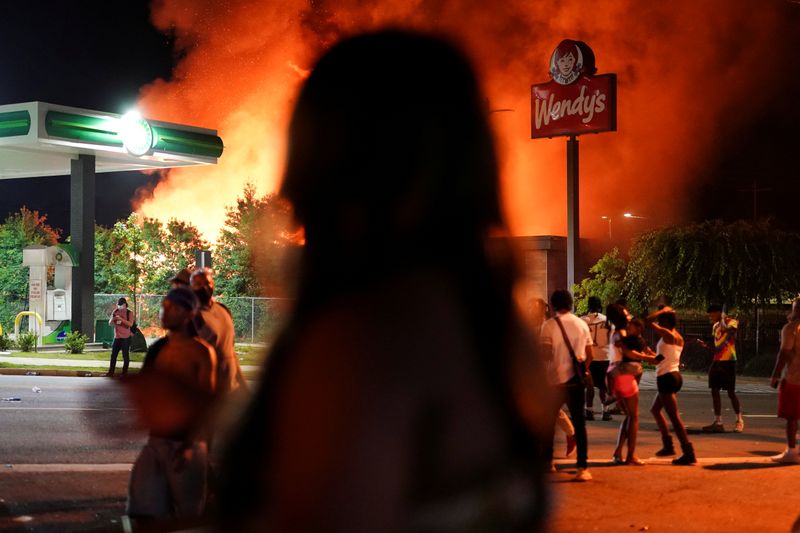 &copy; Reuters. Pessoas observam incêndio em loja da rede de lanchonetes Wendy&apos;s em Atlanta