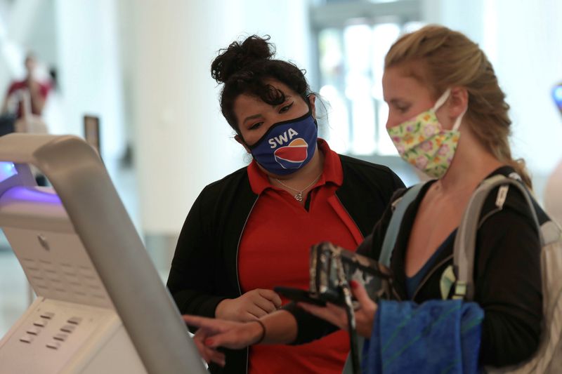 © Reuters. FILE PHOTO: A Southwest Airlines Co. employee wears a protective mask while assisting a passenger at Los Angeles International Airport (LAX) on an unusually empty Memorial Day weekend during the outbreak of the coronavirus disease (COVID-19) in Los Angeles