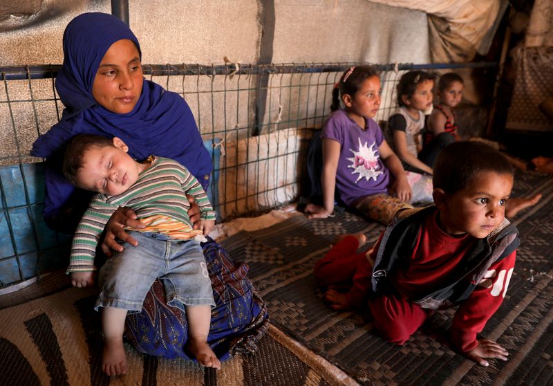 &copy; Reuters. Fawza Umri&apos;s daughter holds her brother on her lap inside their tent, at Atmeh camp, near the Turkish border